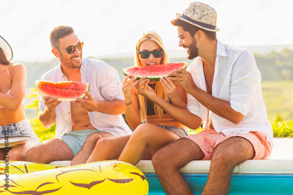Friends eating watermelon at swimming pool party Friends eating watermelon at swimming pool party