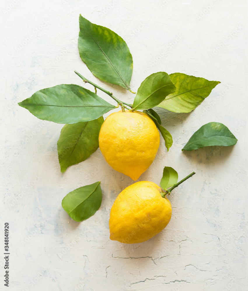 Ripe lemons with green leaves  composition on white desktop background , top view. Organic citrus fruits. Flat lay. Healthy food concept.