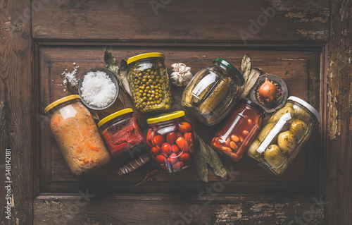 Billede på lærred Homemade marinated and pickles vegetables preserve in jars on rustic wooden background with herbs and spices