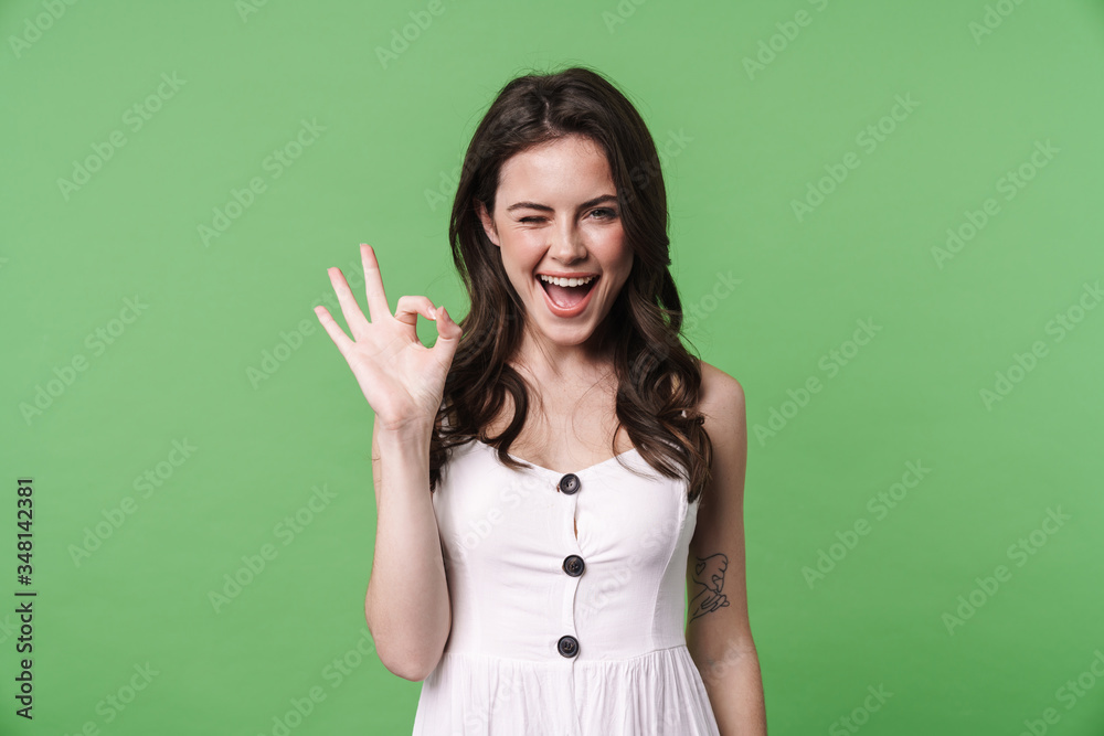 Image of joyful brunette woman winking and showing ok sign Image of joyful brunette woman winking and showing ok sign