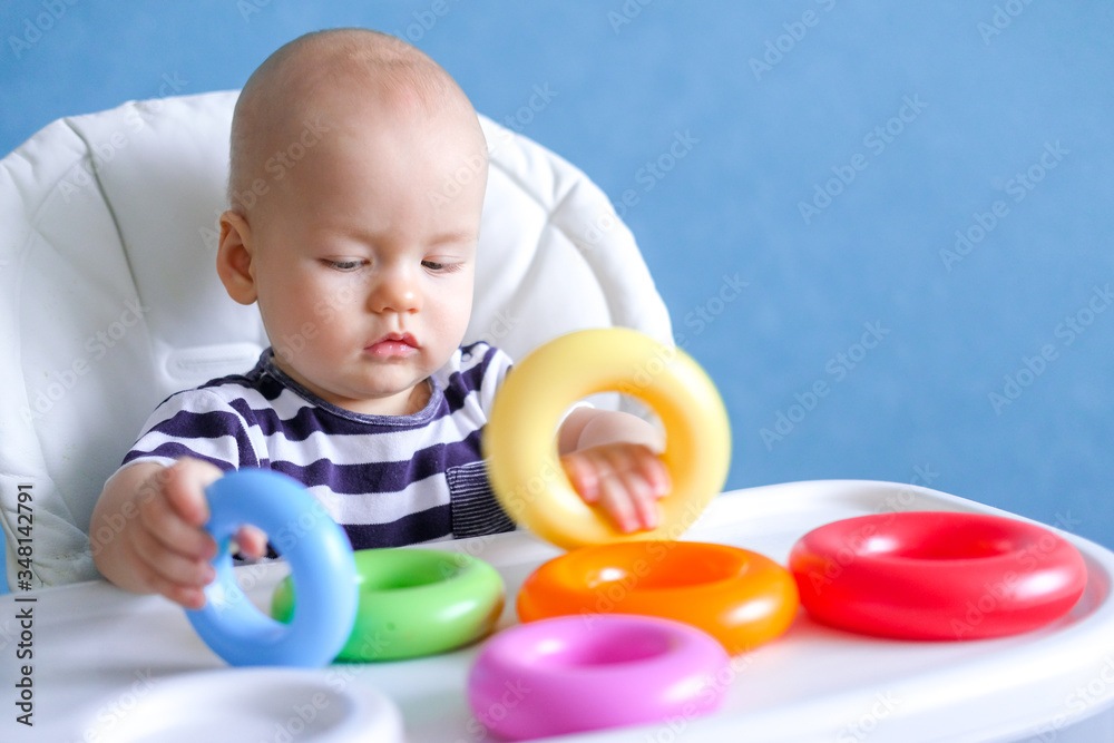 baby game. Little clever caucasian child playing colorful plastic toys pyramid sitting on highchair. games for early development. New born infant kids leisure. baby game. Little clever caucasian child playing colorful plastic toys pyramid sitting on highchair. games for early development. New born infant kids leisure.