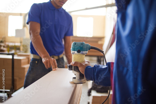 Close up image of a woodworker using a router in a wood furniture manufacturing factory