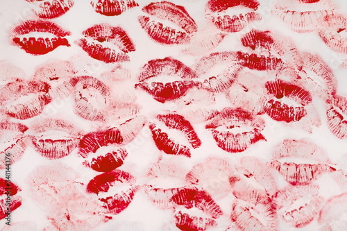 A lot of kissing marks made with the red lipstick on the white paper background - Image. Paper with lipstick kisses. Abstract passion love background.  Imprints of female lips. 