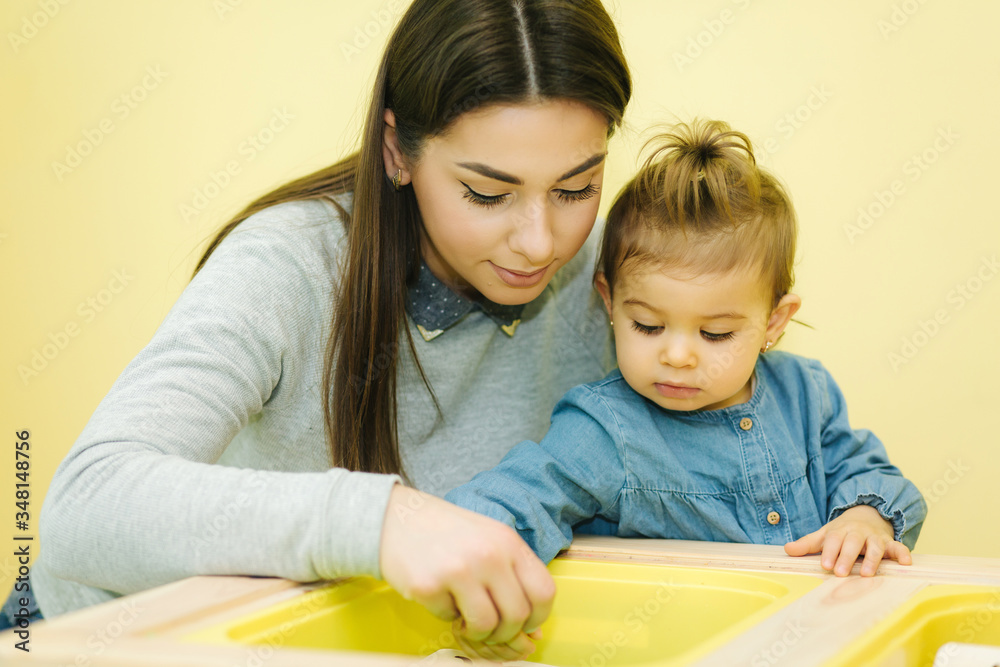 Happy mom play with her daughter in preschool. Cute little girl with mother