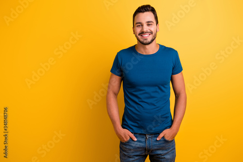 Portrait of his he nice attractive glad cheerful cheery brunette guy holding hands in pockets isolated over bright vivid shine vibrant yellow color background