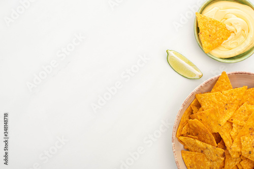 top view of corn nachos with lime and cheese sauce on white background