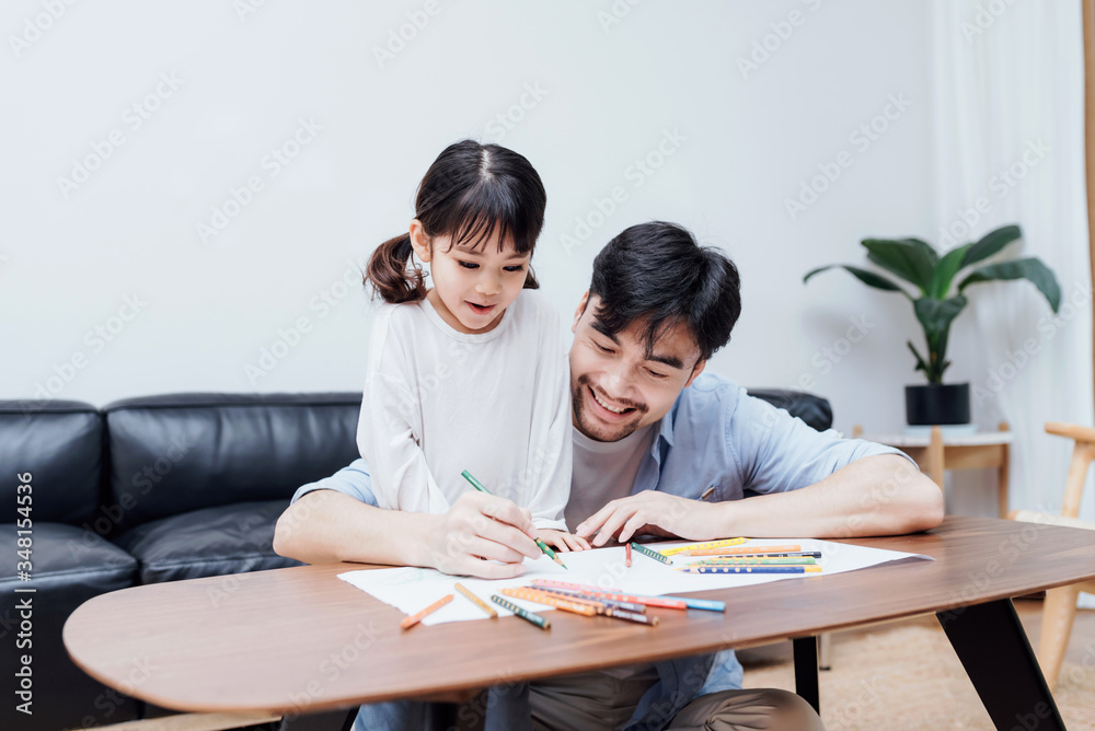 A pair of father and daughter drawing together A pair of father and daughter drawing together