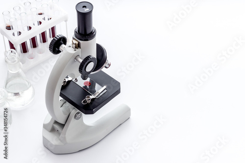 Laboratory examination with microscope. Equipment with blood sample on white background copy space photo