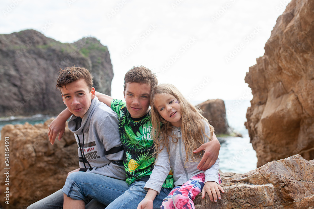 Portrait of happy brothers and sisters on the background of the sea, children walk by the sea