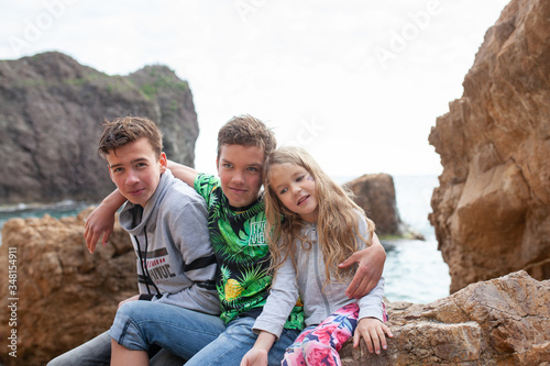 Portrait of happy brothers and sisters on the background of the sea, children walk by the sea © rimmdream