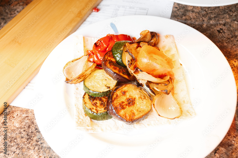 A bowl of spicy grilled vegetables snack served on pita bread. Healthy salad A bowl of spicy grilled vegetables snack served on pita bread. Healthy salad