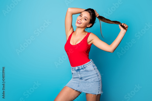 Portrait cheerful cute sweet lady prepare spring weekend walk make pigtails show tongue out enjoy new silky hair effect lotion wear red singlet tank-top jeans isolated blue color background © deagreez