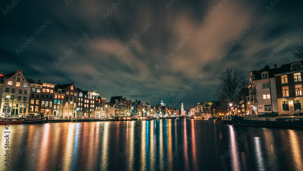 Obraz premium Amsterdam canal, Amstel river with city illumination reflection, Netherlands, Dutch city at night.