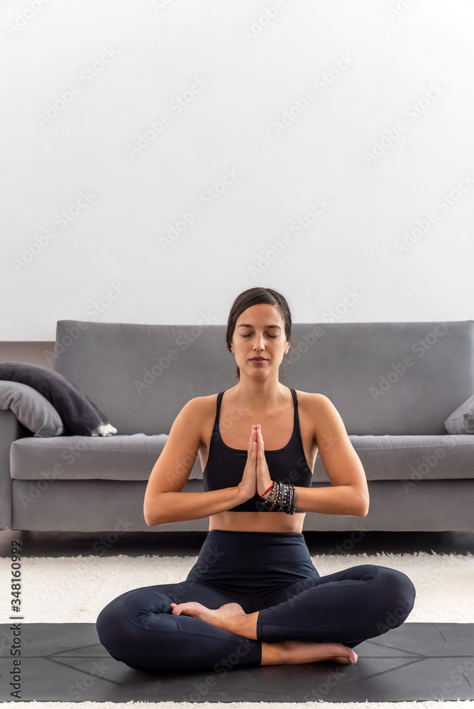 Attractive woman sitting on lotus position with her eyes closed at home