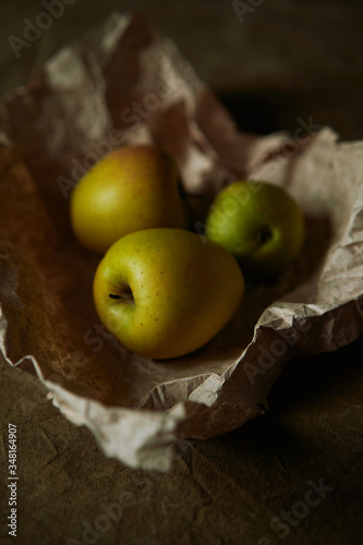 Still life with ripe apples in craft paper in warm tones.