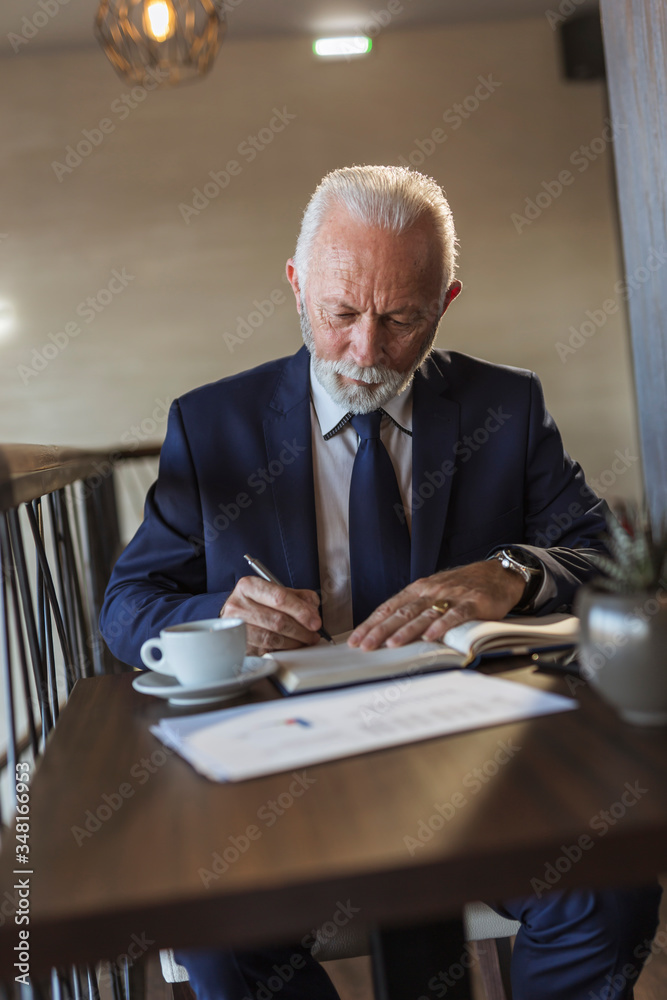 Senior businessman writing in a planner Senior businessman writing in a planner