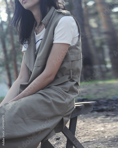 young woman in beige clothes resting on a chair on the nature in a pine forest © uventa