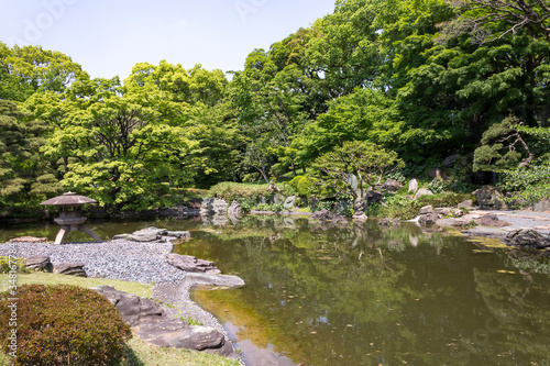 Japanese lantern in the green garden with koi pond
