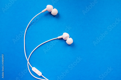 White earphones on a blue background close-up