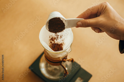 Fotografie Hands pouring grounded coffee in filter pour over on glass kettle on scale