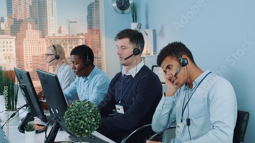 Foto Bored and dissatisfied black call center agent talking to the client on phone