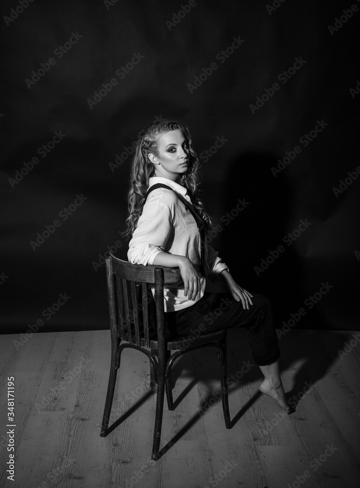 vertical black and white portrait of a pretty barefoot blonde sitting on a chair in the studio vertical black and white portrait of a pretty barefoot blonde sitting on a chair in the studio