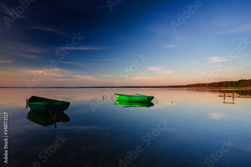 A calm dawn on a lake with boats in the water photo