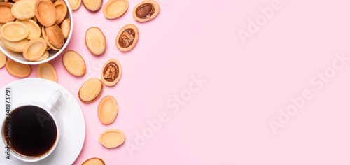 Homemade Russian nuts with condensed milk on a light pink background, wafer napkin. Cut nuts with condensed milk. Bitten goodies for coffee.