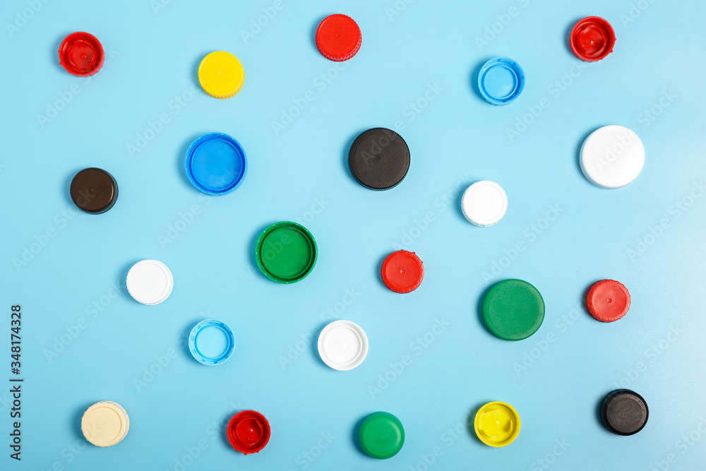  Multi-colored plastic bottle caps on a blue background. The problem of environmental pollution. Top view, Pattern. Recycling plastic.