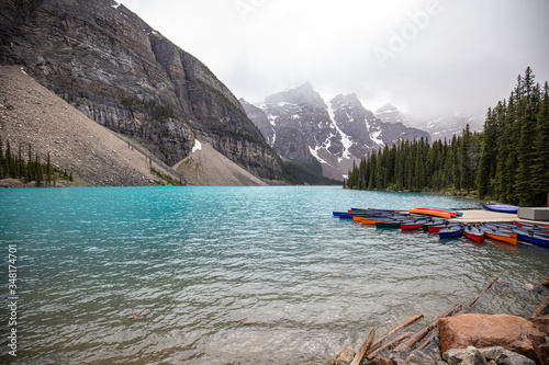 Moraine Lake in Canada with turquoise colour and canoes during a foggy day