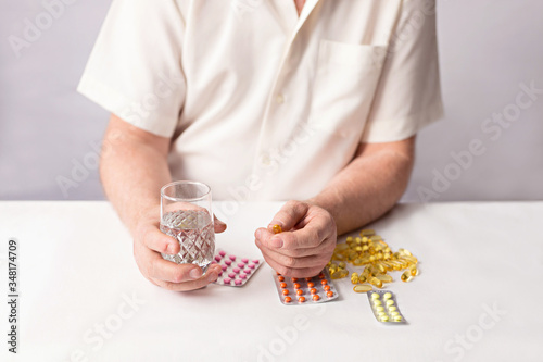 Senior hands with pills and medicine on the table. Wrinkled hand of an old woman holding colorful pills. Old age. Health care for the elderly.