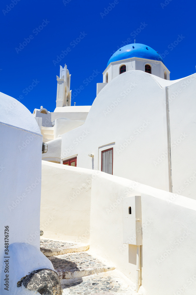 White church with blue dome in Oia town on Santorini island, Greece