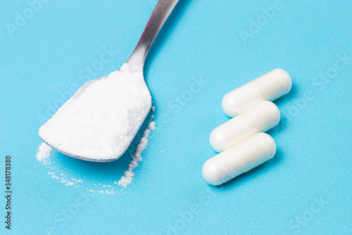 White collagen powder and capsules on blue background, copy space