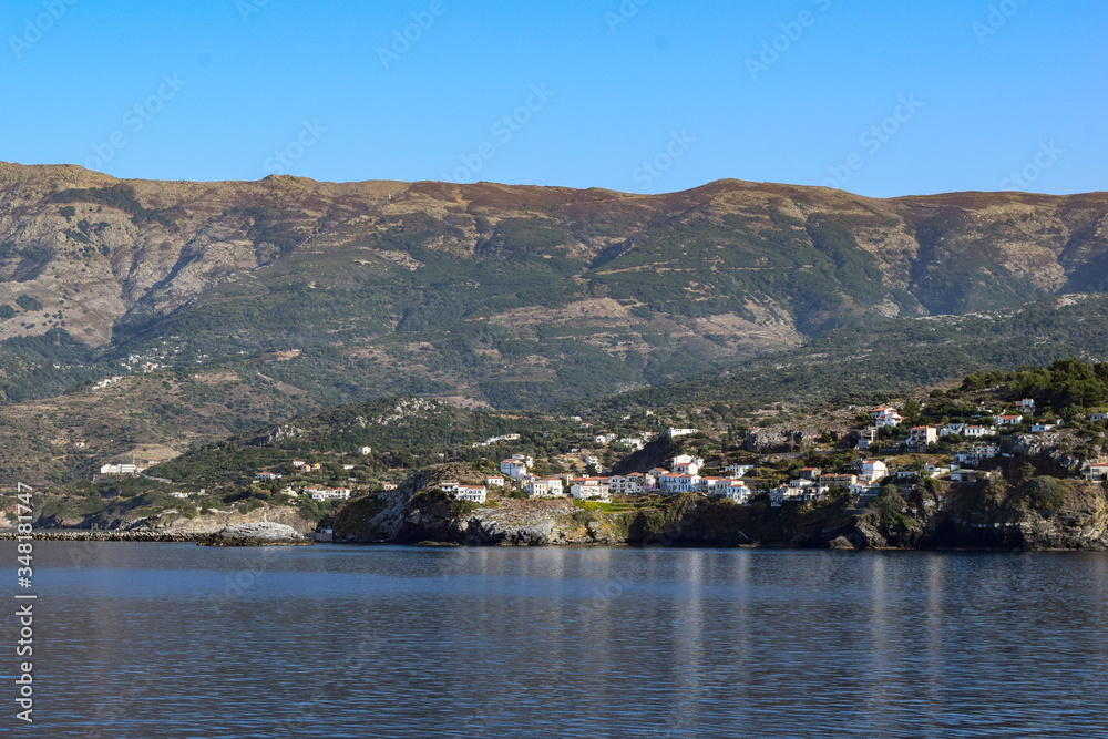Greek towns on the island of Ikaria with mountains behind. Sailing through the Mediterranean Sea.