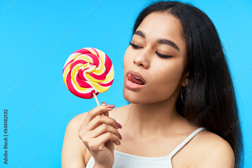 Young pretty black woman licking colorful lollipop