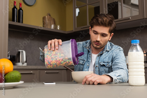 Cuadro en lienzo Selective focus of man pouring cereals in bowl near bottle of milk and fruits on