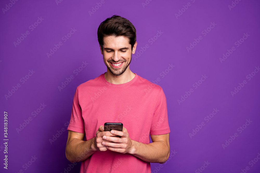 Portrait of positive cheerful guy use smartphone read social network news post comment feedback wear style stylish clothes isolated over shine color background Portrait of positive cheerful guy use smartphone read social network news post comment feedback wear style stylish clothes isolated over shine color background