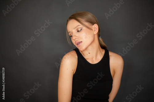 beautiful, cute girl peeking to the side over her shoulder on a dark background in the studio. emotions
