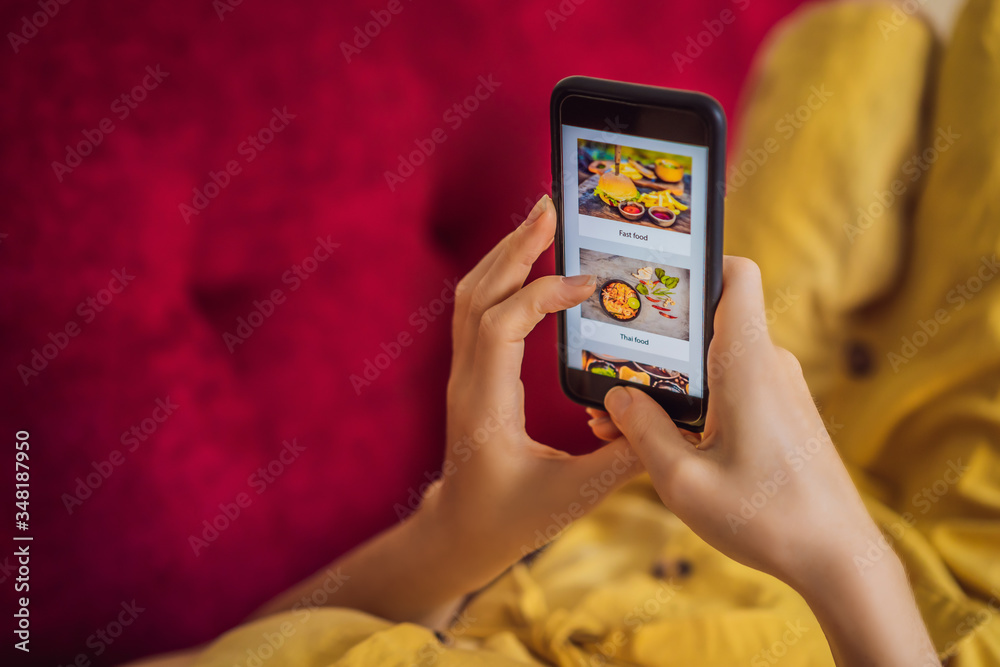© galitskaya - Young woman orders food for lunch online using a smartphone