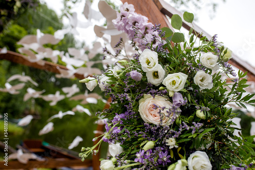 Wooden round arch for the ceremony.Close-up of flower arrangements on the arch