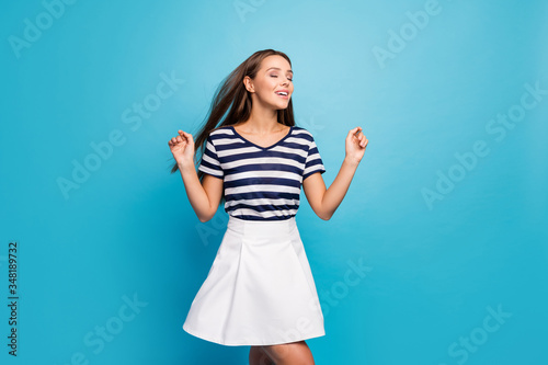 Photo of amazing lady traveler walking street enjoy warm summer breeze long hairstyle flying eyes closed wear white striped sun mini summer dress isolated blue background
