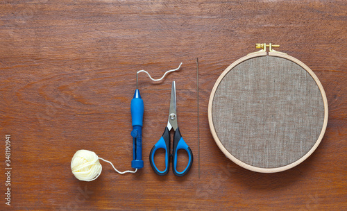 Needlework. A special multi-level needle for embroidery with woolen threads using the technique of punching gobelin or carpet technique and a stretched linen canvas in a hoop on wooden background photo