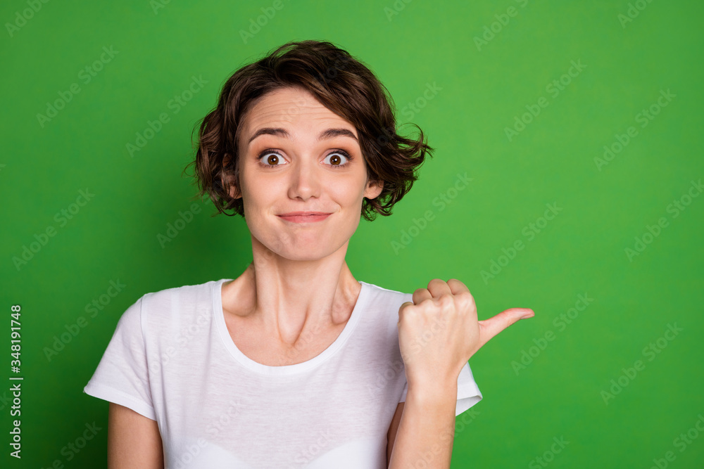 Photo of attractive lady short wavy hairdo direct thumb finger side empty space showing amazing novelty offer banner wear casual white t-shirt isolated green color background Photo of attractive lady short wavy hairdo direct thumb finger side empty space showing amazing novelty offer banner wear casual white t-shirt isolated green color background