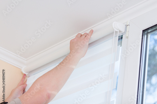 Man hands installing window roller duo system day and night.