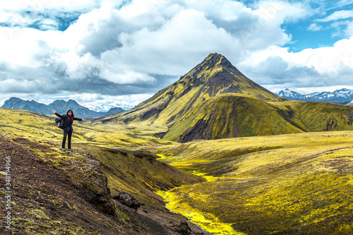 A young woman on a green mountain and a beautiful river of moss on the 54 km trek from Landmannalaugar  Iceland