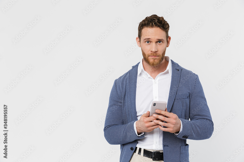 Image of confident handsome man wearing jacket typing on smartphone Image of confident handsome man wearing jacket typing on smartphone