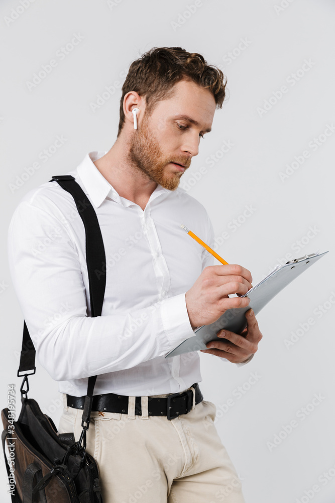 Image of focused man in wireless earphones holding clipboard and writing Image of focused man in wireless earphones holding clipboard and writing