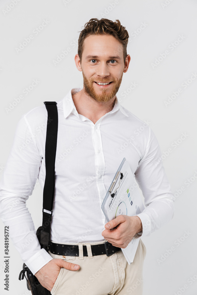 Image of cheerful man smiling while posing with clipboard and bag Image of cheerful man smiling while posing with clipboard and bag