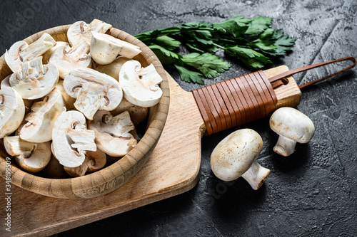 Chopped champignons in a wooden bowl. Black background. Top view