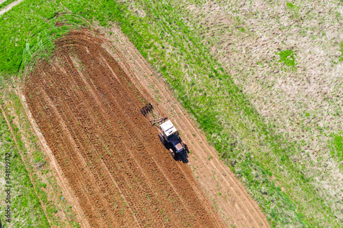 Tractor plows a small field in the village before planting vegetables. Aerial height view.